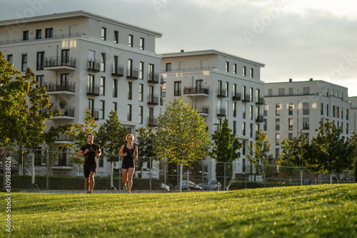 Wallpaper Mural Two young attractive athletes run in the park of a modern city Torontodigital.ca