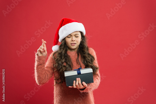 please. christmas holiday party. small girl in santa hat. cheerful child red wall. kid shopping sales. xmas boxing day. best christmas offer. little girl hold present box. happy new year gift