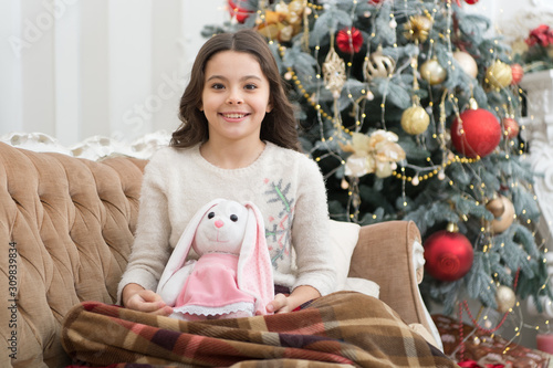 Lets celebrate. feeling cosy at home. happy new year mood. happiness and joy. ready for xmas presents. small girl love her bunny. best christmas toy. cheerful kid play toy at christmas tree photo