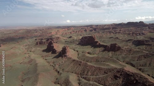 Flying over the Chinese Grand Canyon also known as Pingshan Grand Canyon in Gansu province, China. Beautiful steep brown hills, and sky slightly covered by clouds in the background.
