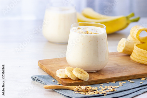 Vegan banana and oatmeal smoothie in glass jar on the light background. Healthy food.
