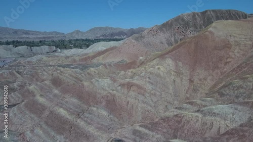 Flying over the Zhangye Danxia Landform Geological Park known also like the rainbow mountains with its colorful hills and clear blue sky in the background in Gansu province, China.