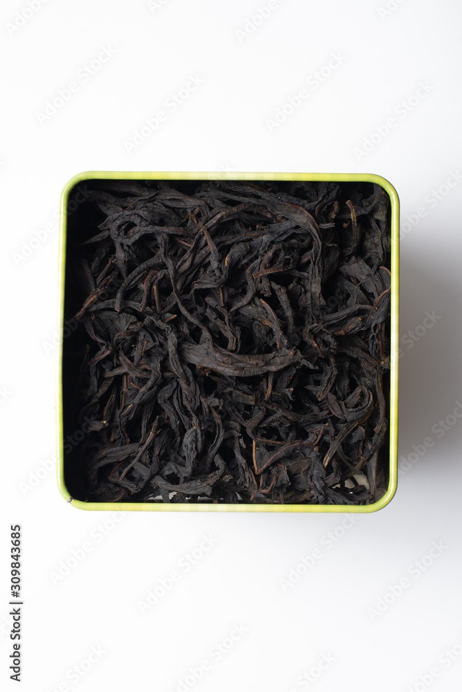 Large fermented willow-tea leaves in a square tin can. Isolate on a white background. Large fermented willow-tea leaves in a square tin can. Isolate on a white background.