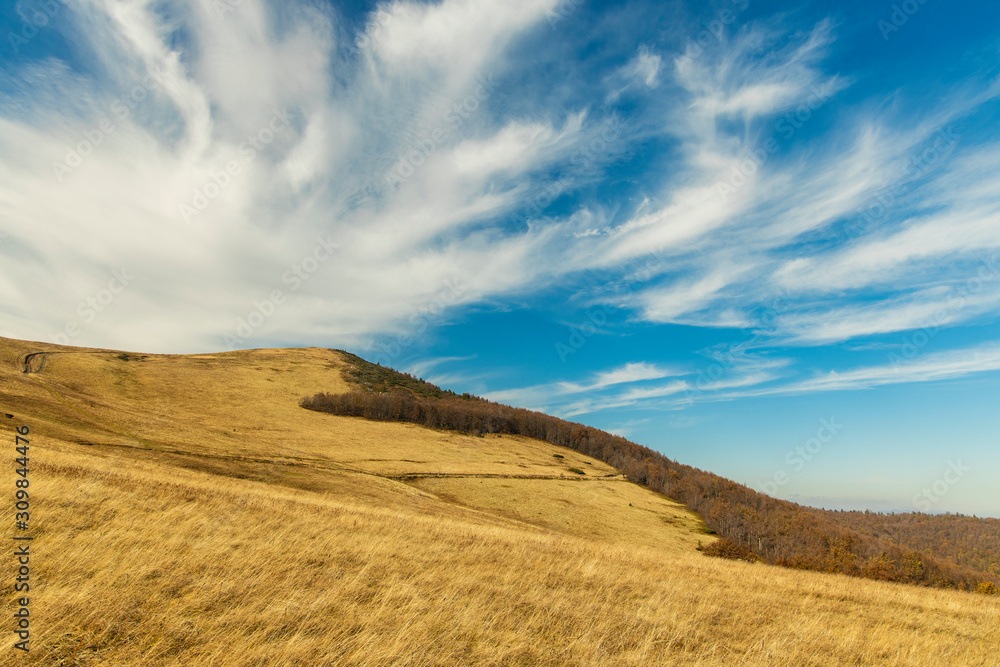 mountains hill dry grass land highland environment scenic view photography in clear weather day time and vivid blue sky fluffy white clouds background