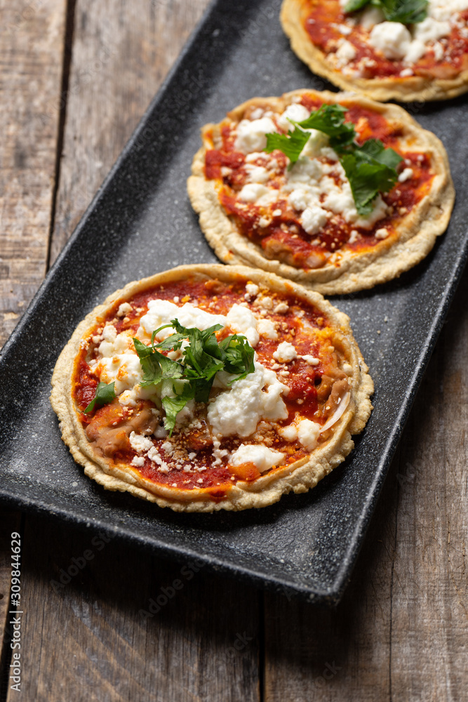 Mexican sopes with red sauce and fresh cheese on wooden background Mexican sopes with red sauce and fresh cheese on wooden background