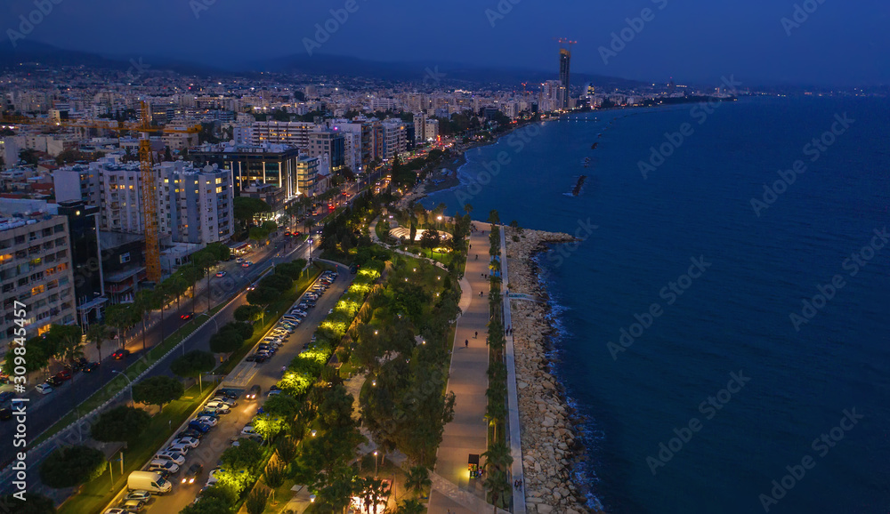 Aerial view of Limassol promenade or embankment with alley and buildings in Cyprus at night. Drone photo of mediterranean sea resort Limassol from above.