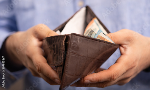 Hands opening a leather wallet with Euro banknotes inside