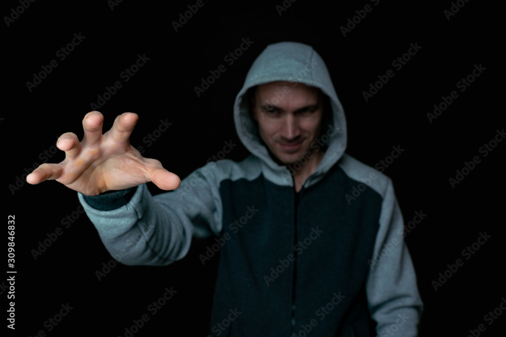 Naklejka premium robber in the hood pulls his hand out of the dark
