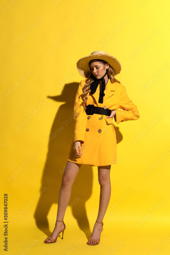 Pretty blonde girl with freckles in yellow outfit and straw hat on yellow background Pretty blonde girl with freckles in yellow outfit and straw hat on yellow background