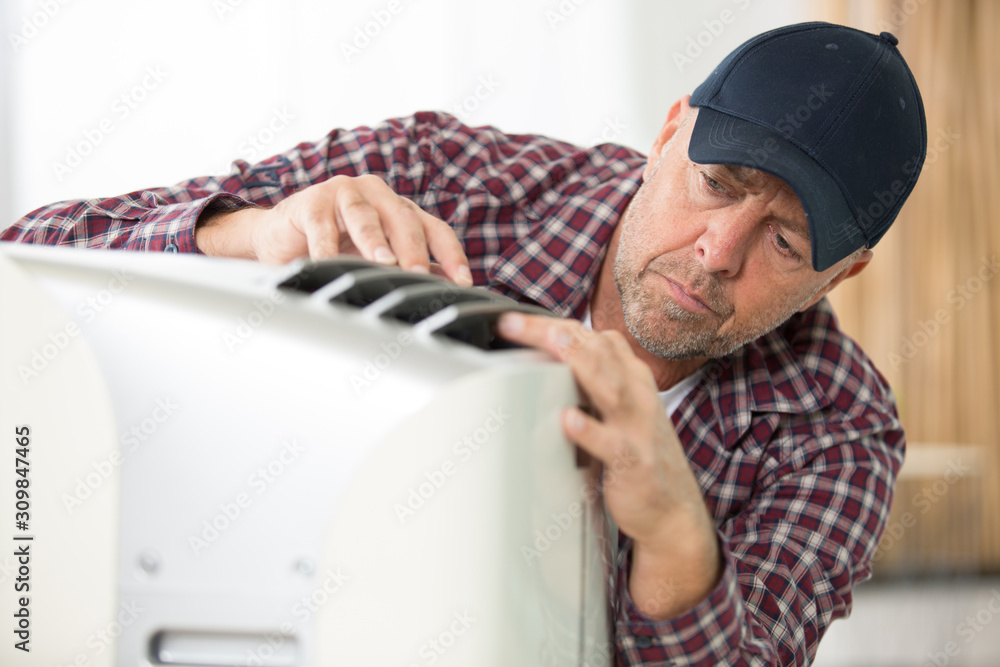male technician cleaning air conditioner indoors