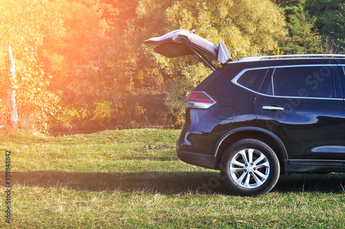 Crossover car with opened boot in a park with trees and sunlight