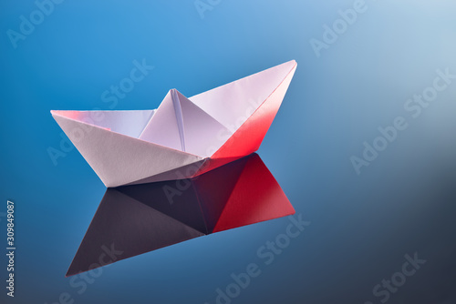 colorful paper boat on a mirror surface