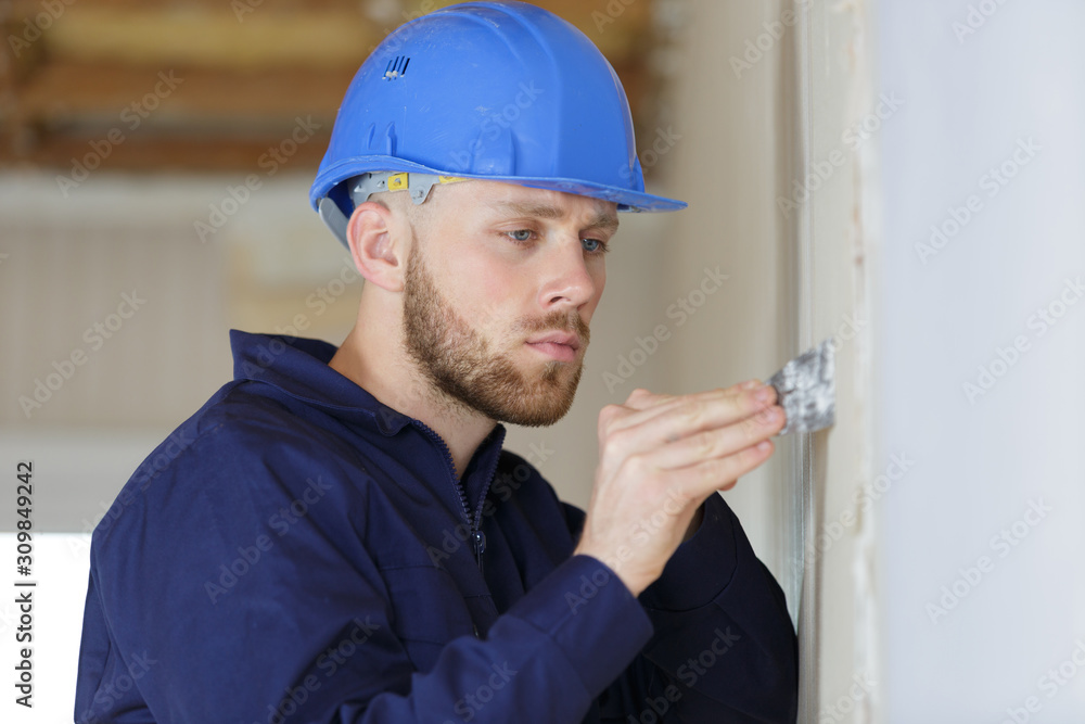 male builder using putty knife on white wall male builder using putty knife on white wall