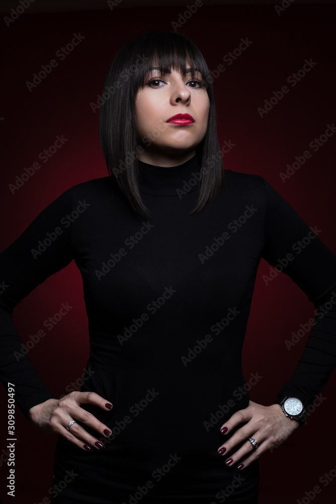 Young beautiful girl in a business style in black clothes with haircut on red background. Studio shot. Young beautiful girl in a business style in black clothes with haircut on red background. Studio shot.