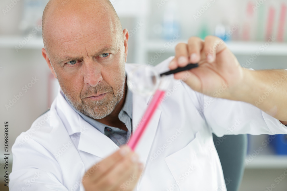mature scientist holding flask in chemical lab mature scientist holding flask in chemical lab