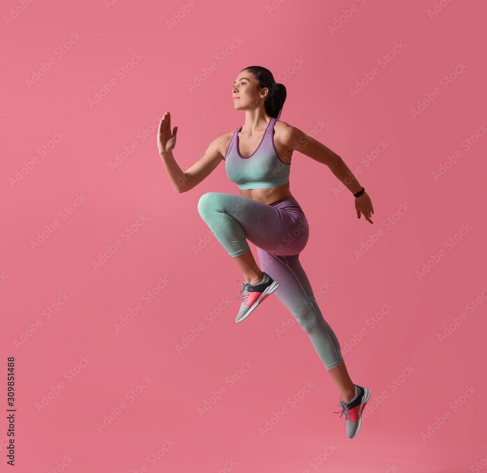 Athletic young woman running on pink background, side view