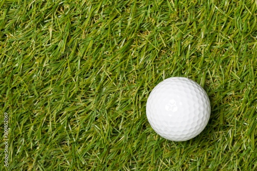 Obraz na plátne White golf ball on green grass lawn with copy space top view flat lay from above