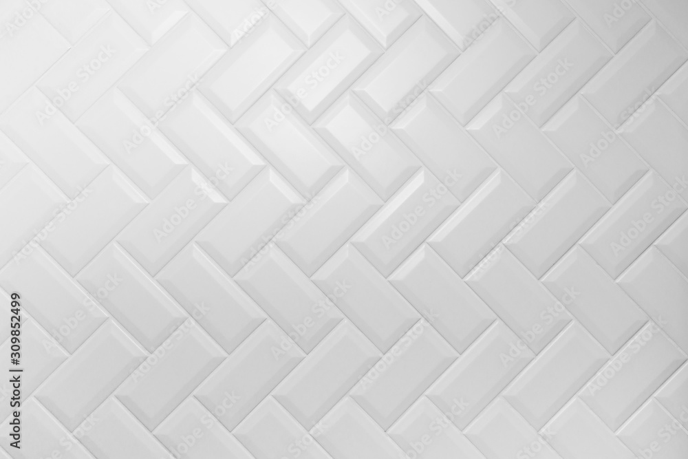 Beveled white matt ceramic tiles pattern herringbone on wall. - obrazy, fototapety, plakaty 