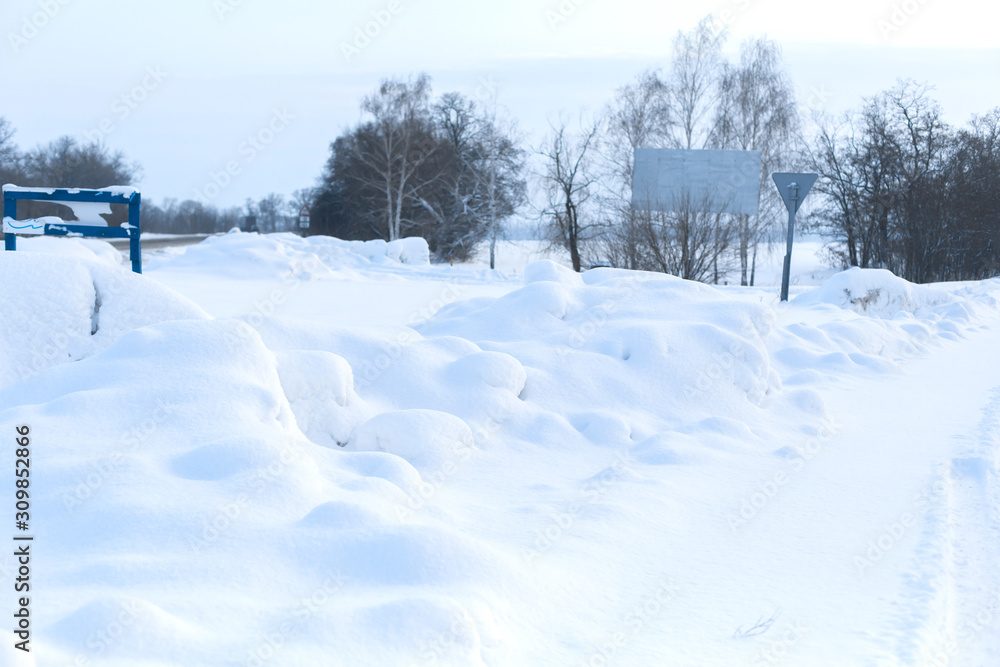 Winter poorly cleared road. Road in the countryside strewn with snow. Winter landscape with snowdrifts Winter poorly cleared road. Road in the countryside strewn with snow. Winter landscape with snowdrifts