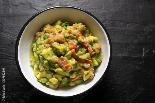 Mexican guacamole with tomato on dark  background