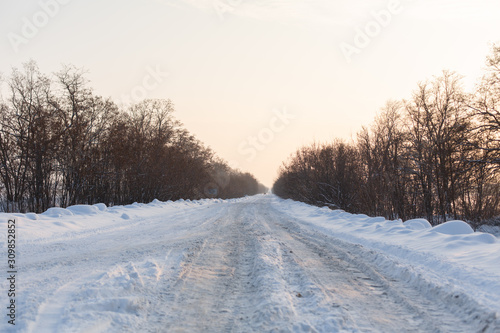 Winter poorly cleared road. Road in the countryside strewn with snow. Winter landscape with snowdrifts © Kate