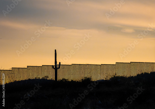 Mexico border wall at southern southern Arizona border with iconic Saguaro cactus in foreground 