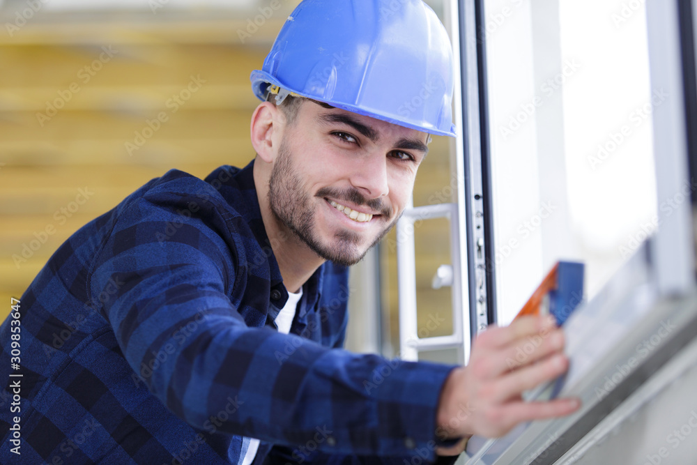 happy young worker checks the level of a window happy young worker checks the level of a window