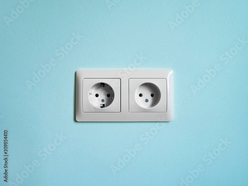 Electric double socket on the aquamarine wall.