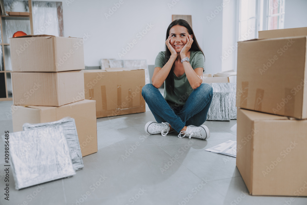 Smiling woman sitting in the middle of cardboard boxes Smiling woman sitting in the middle of cardboard boxes