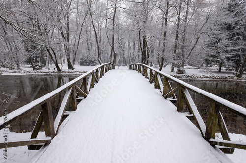 Wooden bridge covered with snow. Snowy and cold day in the park. Winter background