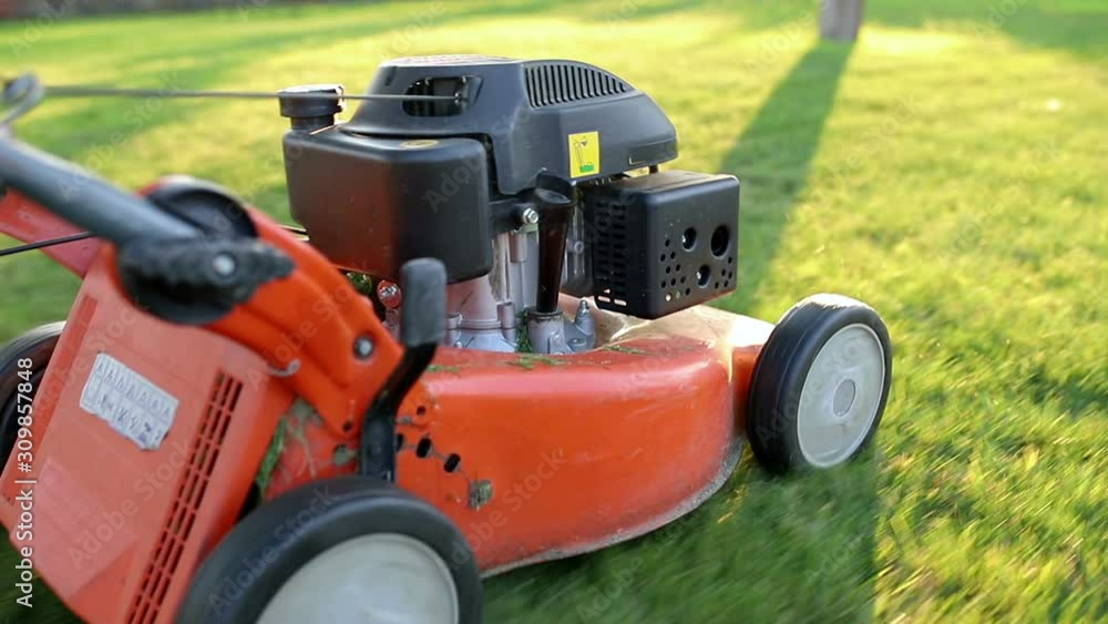 Homeowner working in garden uses lawnmower to mow a lawn. Homeowner working in garden uses lawnmower to mow a lawn.