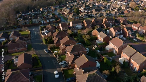Aerial footage panning down over a housing estate next to a large field during a low sun and a golden sunrise in Hornsea, East Yorkshire, UK