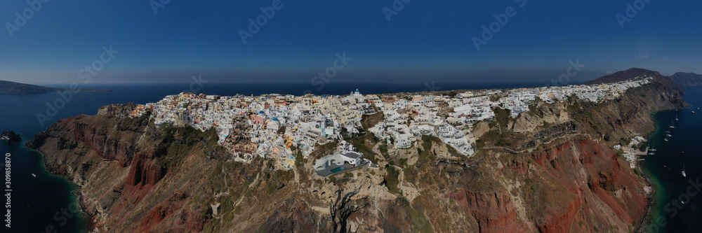 Aerial drone panoramic photo of world famous picturesque village of Oia in volcanic island of Santorini, Cyclades, Greece