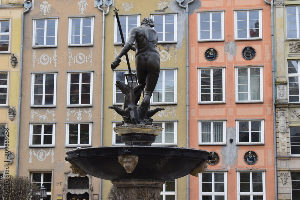 Neptune fountain designed by Abraham van den Blocke in Gdansk old town center. Bronze statue of the Roman sea god at the center of Long market. Colorful facades at the background.