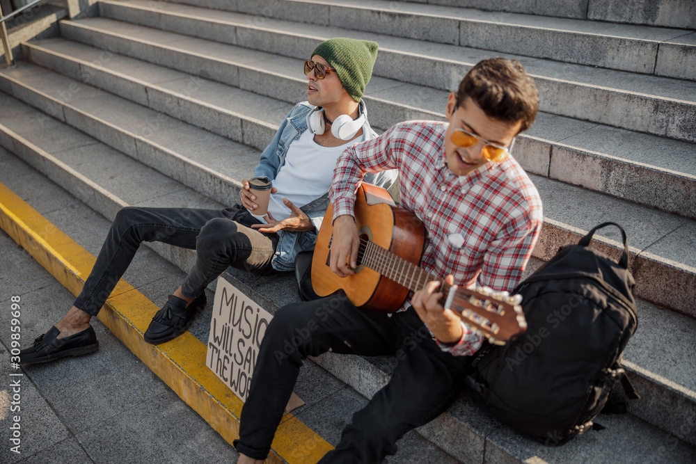 Young musician enthusiastically playing guitar on the street