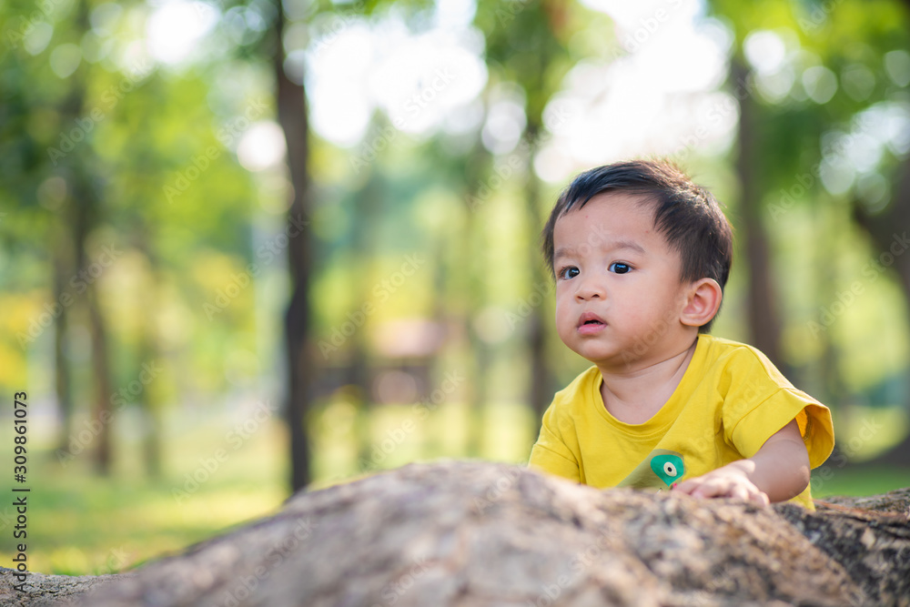 Adorable baby boy playing ujnder tree in city park sunset light Adorable baby boy playing ujnder tree in city park sunset light