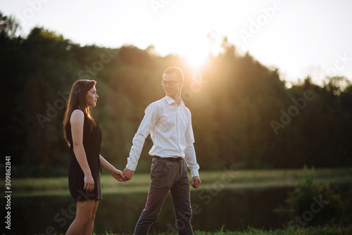 guy leads the girl by the sunset, holding her hand