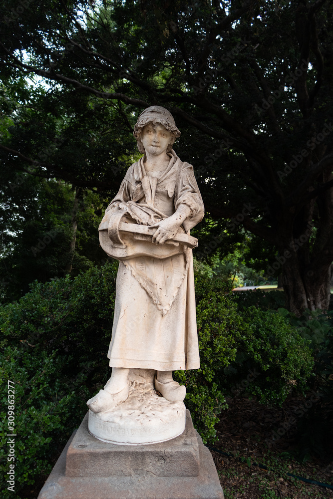 'Linda da Chamonix' statue in garden bed 81. Marble Victorian-era pair of statues of a young girl with a scarf, clogs and musical instrument and a sweep boy from the Donizetti opera 'Linda da Chamonix' statue in garden bed 81. Marble Victorian-era pair of statues of a young girl with a scarf, clogs and musical instrument and a sweep boy from the Donizetti opera