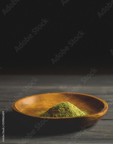 Mitragynina speciosa or Kratom powder in wooden bowl on table photo