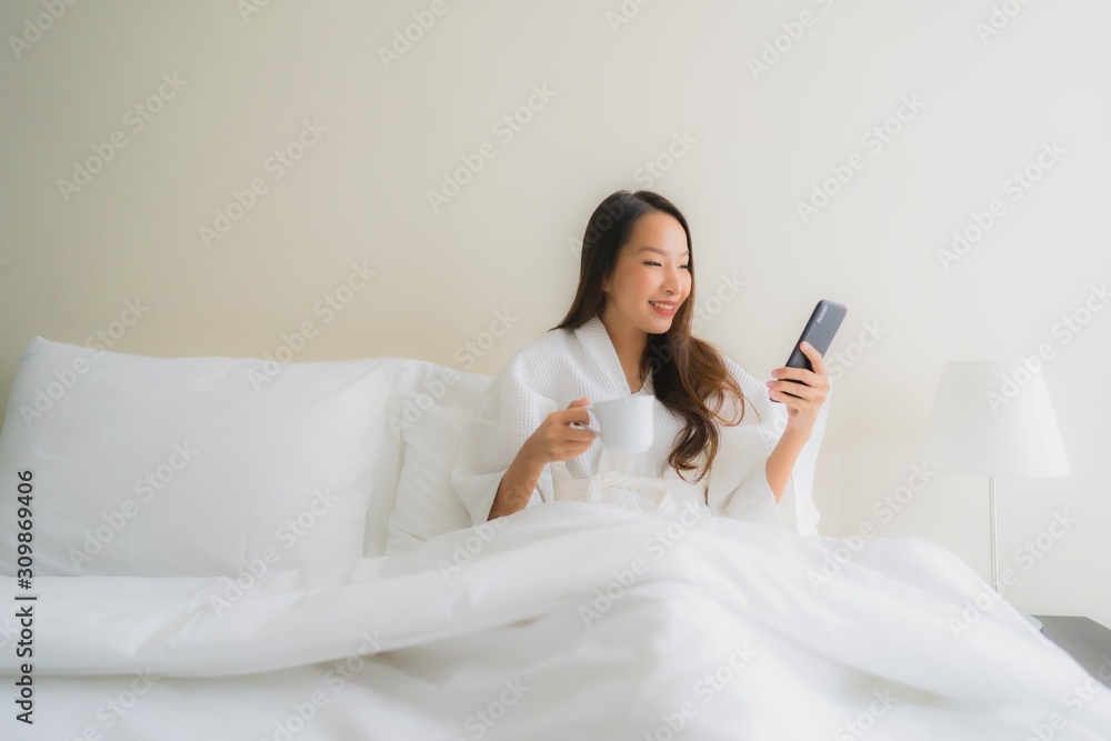 Portrait beautiful young asian women with coffee cup and mobile phone on bed Portrait beautiful young asian women with coffee cup and mobile phone on bed