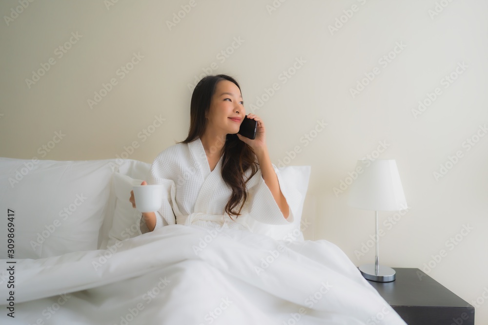 Portrait beautiful young asian women with coffee cup and mobile phone on bed