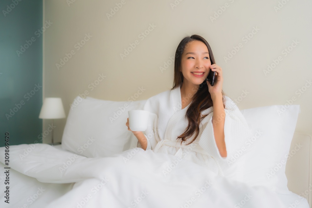Portrait beautiful young asian women with coffee cup and mobile phone on bed Portrait beautiful young asian women with coffee cup and mobile phone on bed
