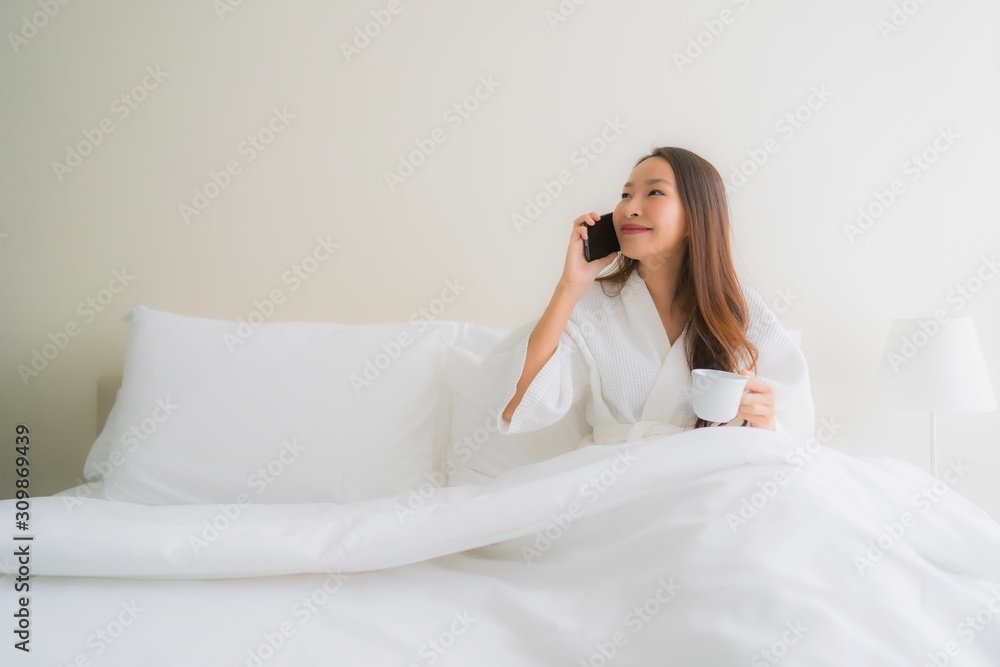 Portrait beautiful young asian women with coffee cup and mobile phone on bed Portrait beautiful young asian women with coffee cup and mobile phone on bed