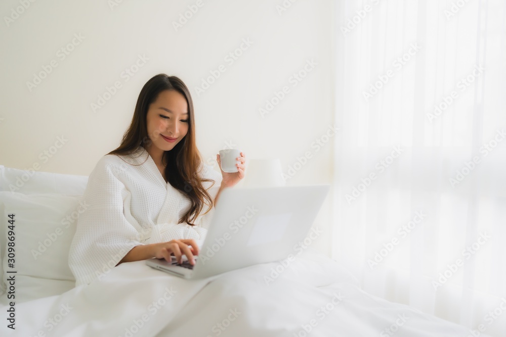 Portrait beautiful young asian women with coffee cup and computer laptop on bed