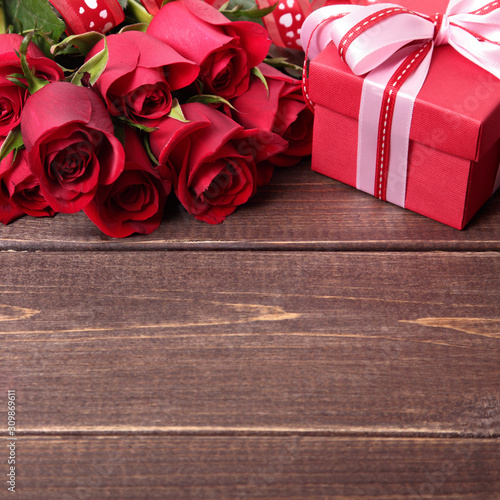 Valentine background of gift box and red roses on wood. Space for copy.