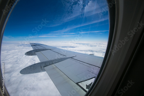 View from the window of the plane onto the wing and engines of a fokker 100 model with a blue sky and white clouds. Sunny weather © Elizaveta