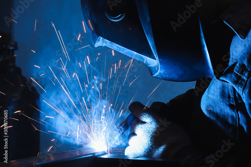 factory welder welds parts with a semi-automatic welding machine photo