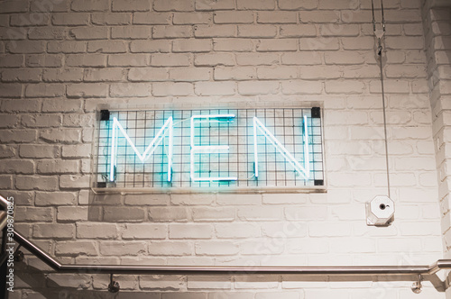 neon sign on white brick wall saying men. Sign in shop for men section. background picture