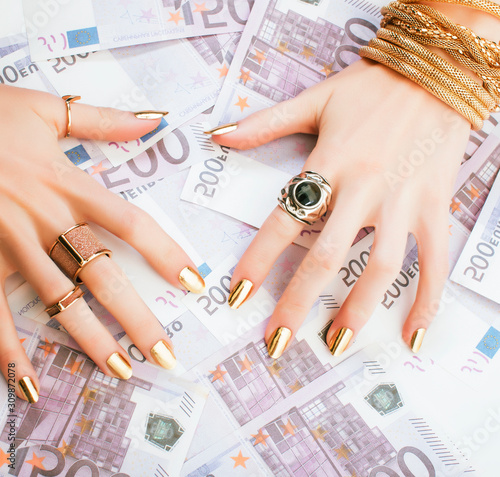 Obraz na plátně hands of rich woman with golden manicure and many jewelry rings on cash euros