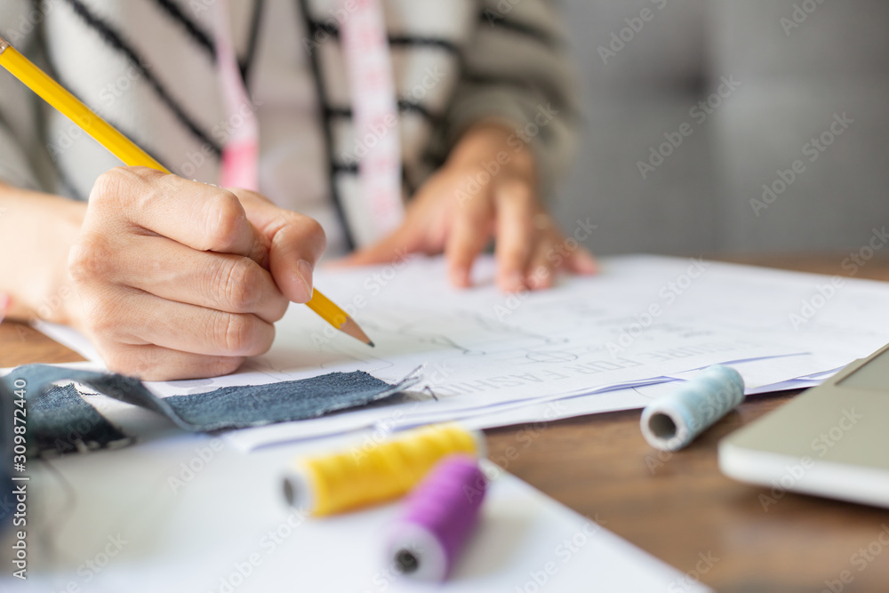 fashion designer drawing and sketche working on desk with tailor equipment in studio.stylish making a pattern fashion designer drawing and sketche working on desk with tailor equipment in studio.stylish making a pattern